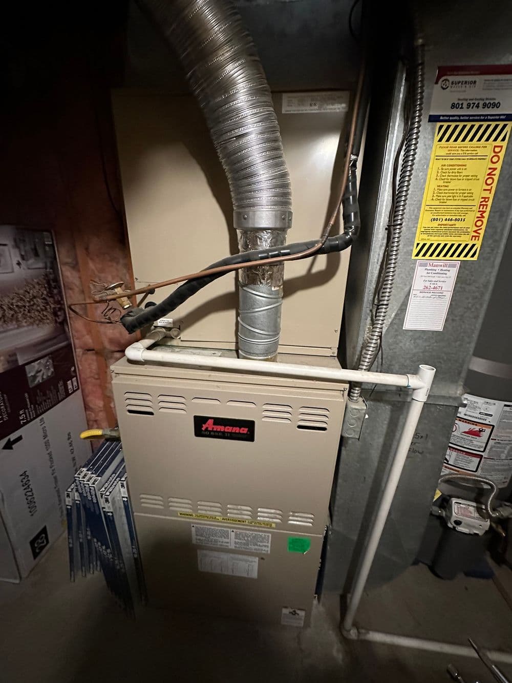Amana gas furnace with ductwork in a basement setting, showcasing heating system details.