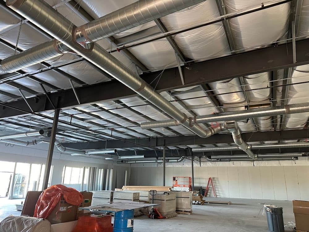 Industrial interior of a construction site with exposed ductwork and construction materials.