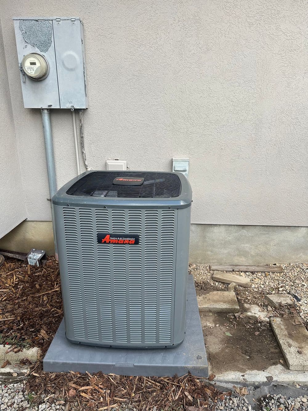 Air conditioning unit installed outside a home with an electrical meter nearby.
