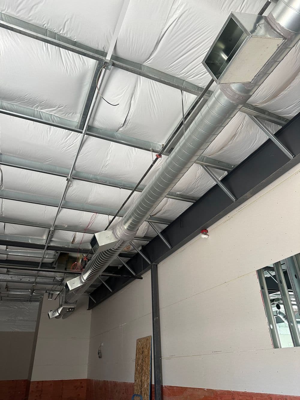 Industrial ceiling with metal ducts and vents in an unfinished commercial space.