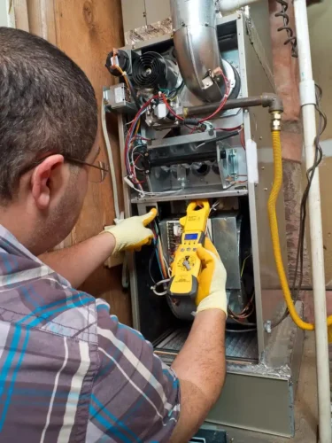 A technician maintaining a furnace installed inside the house